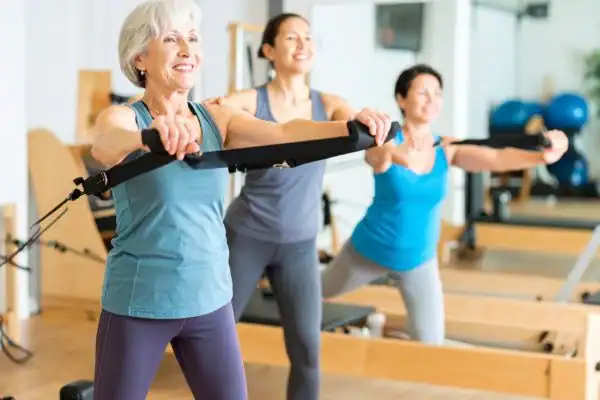 Toning Arms After 60: Empowering Womens Fitness Through Effective Weight Training 2 older woman doing weight training Rushden and resistance in the gym to tone upper arms